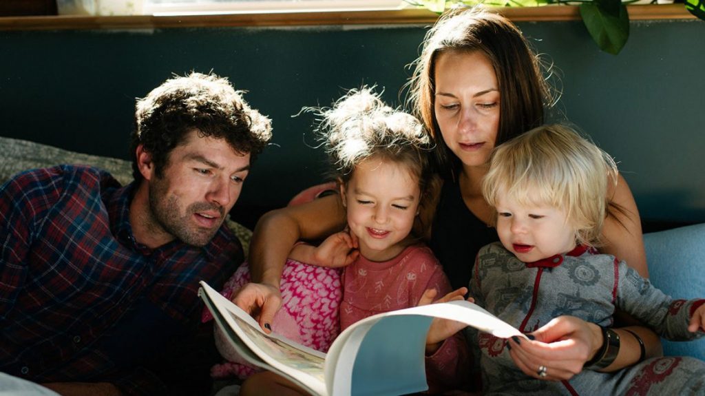 anne ve baba iki çocuğuna kitap okuyor