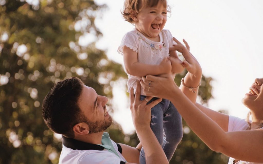 anne ve baba bebeklerini havaya kaldırmış gıdıklıyorlar
