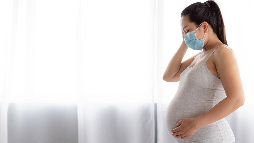 ağzı maskeyle kapalı hamile bir kadın